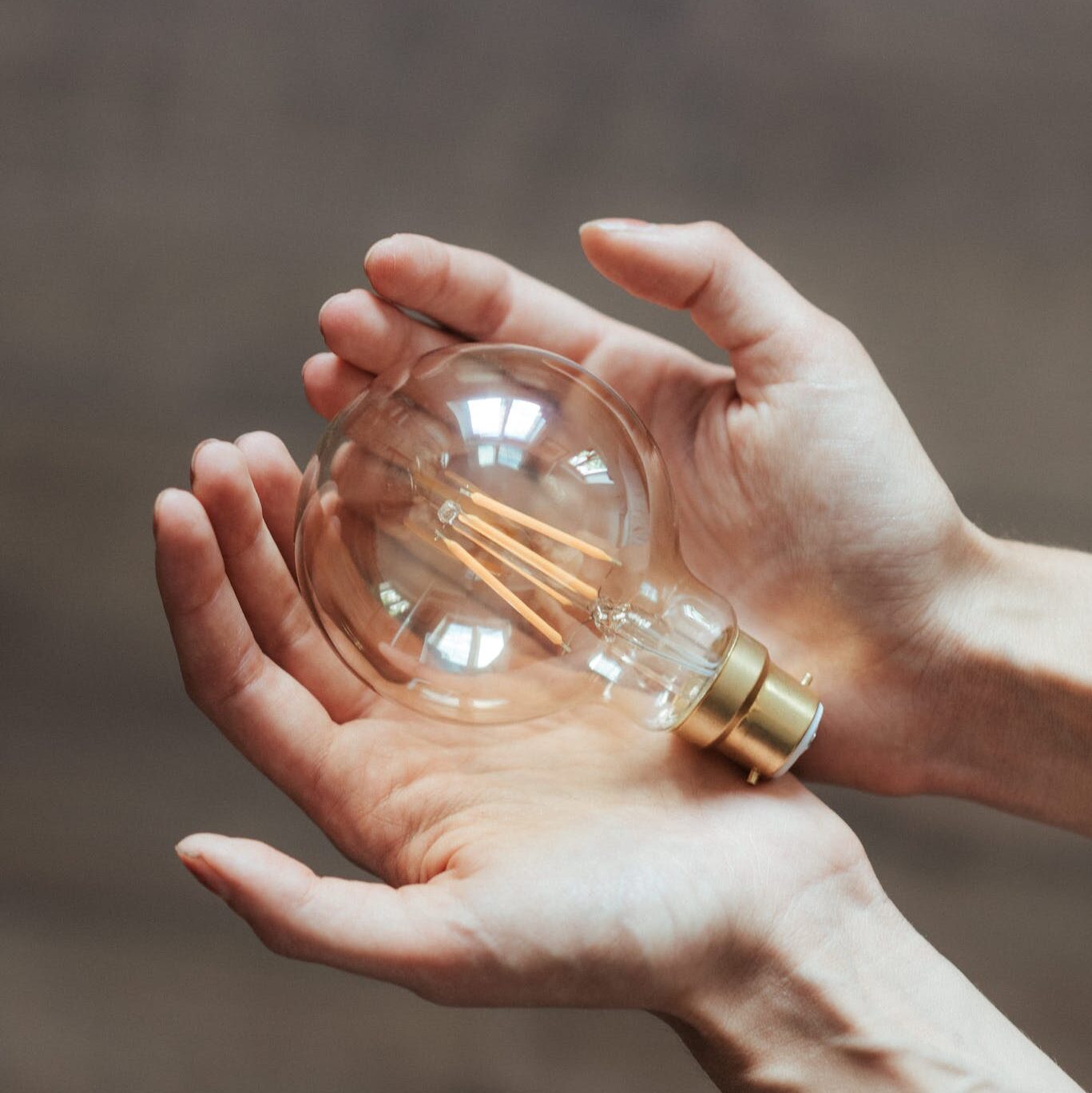 Unrecognizable woman demonstrating light bulb in hands